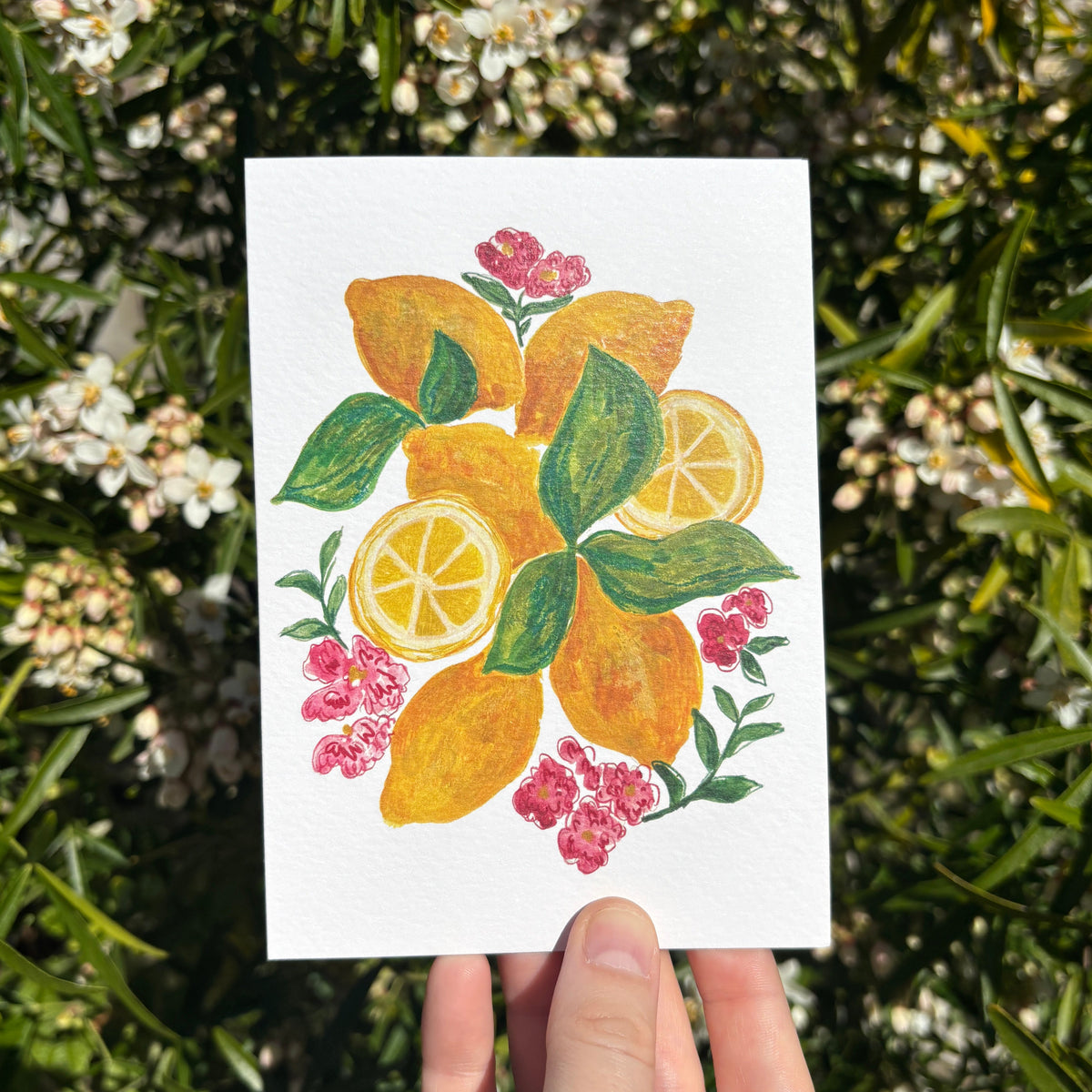 Greeting card with an illustration of lemons pink flowers held against a floral background.