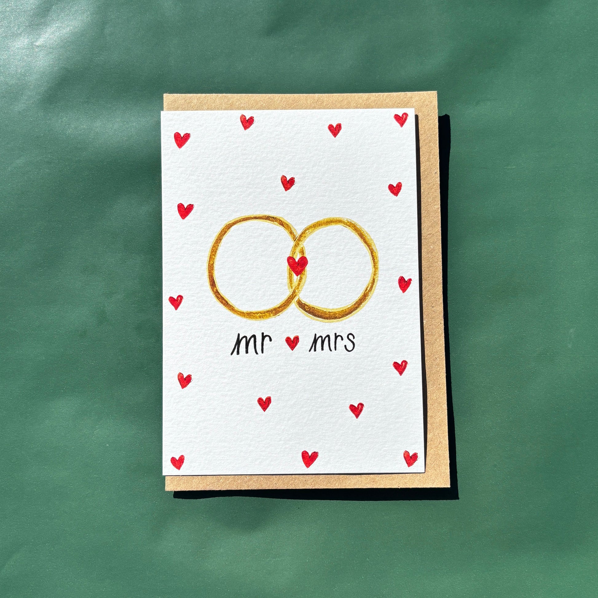 A greeting card featuring an illustration of wedding rings and tiny love hearts with "Mr and Mrs" text