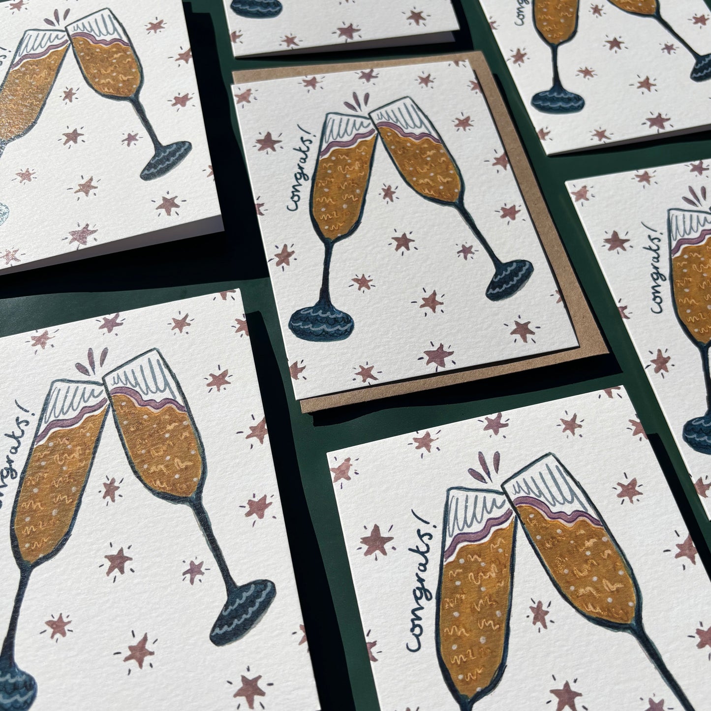 Multiple greeting cards with illustrations of champagne glasses and "congrats" text.