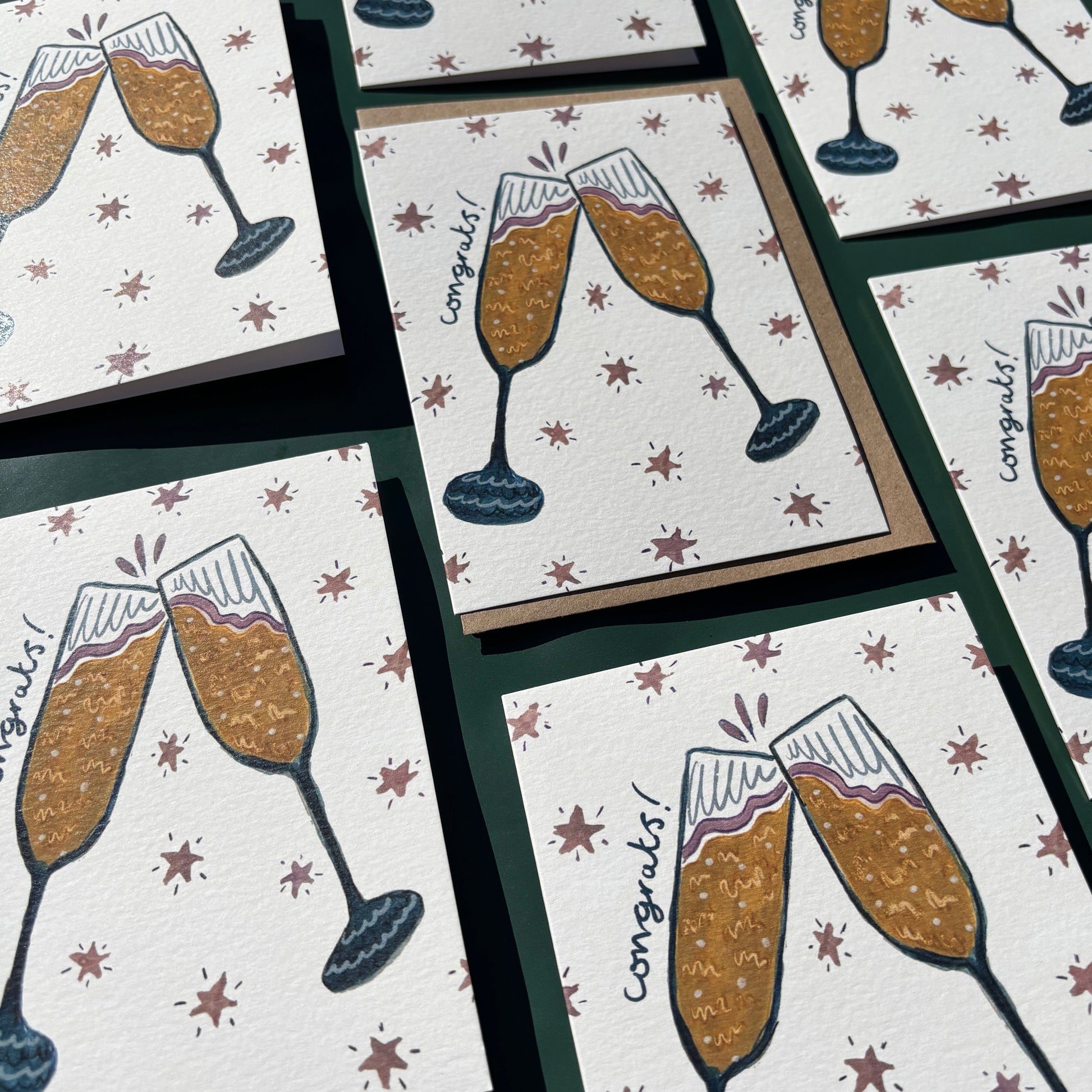 Multiple greeting cards with illustrations of champagne glasses and "congrats" text.