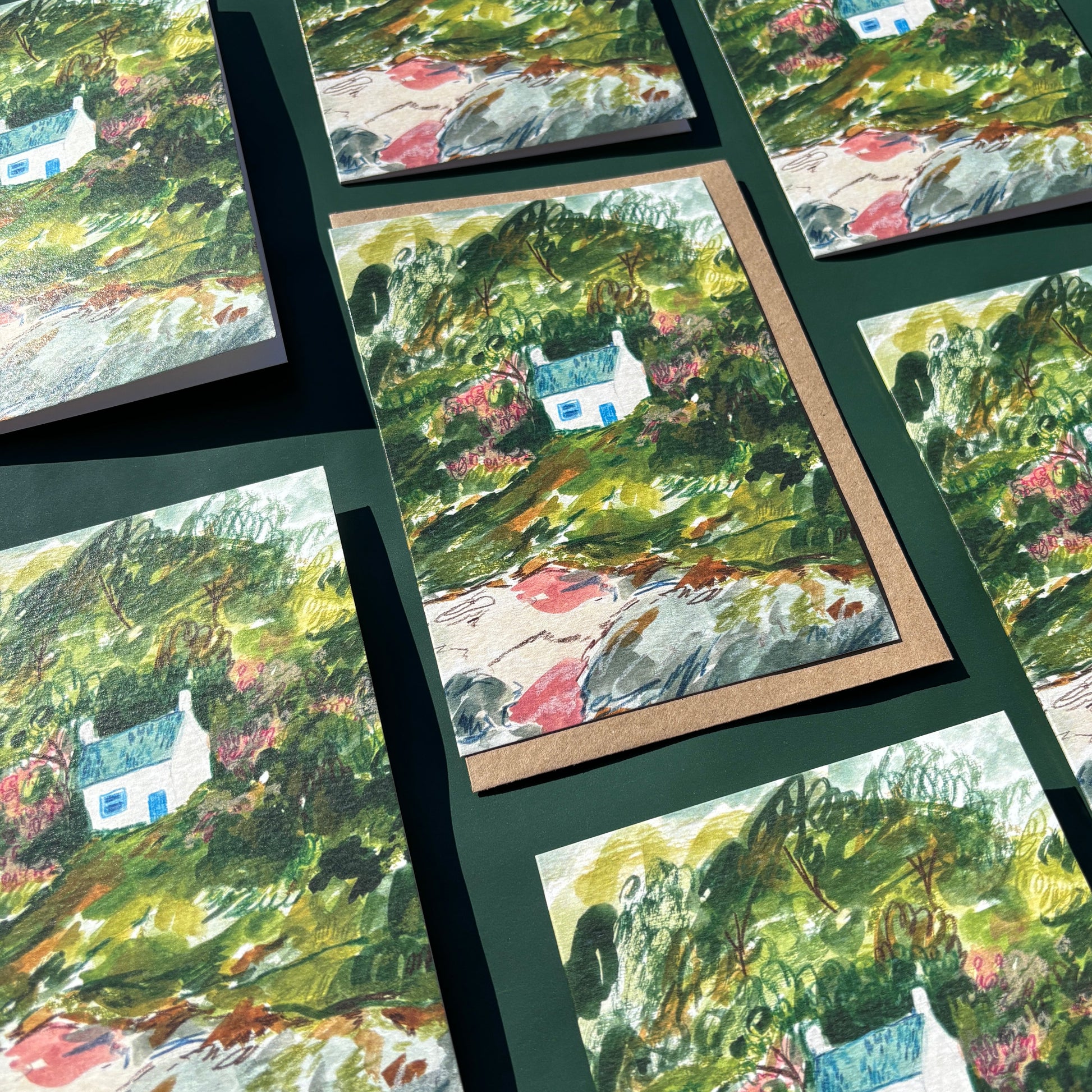 Multiple cards featuring a painting of a seaside cottage within a landscape