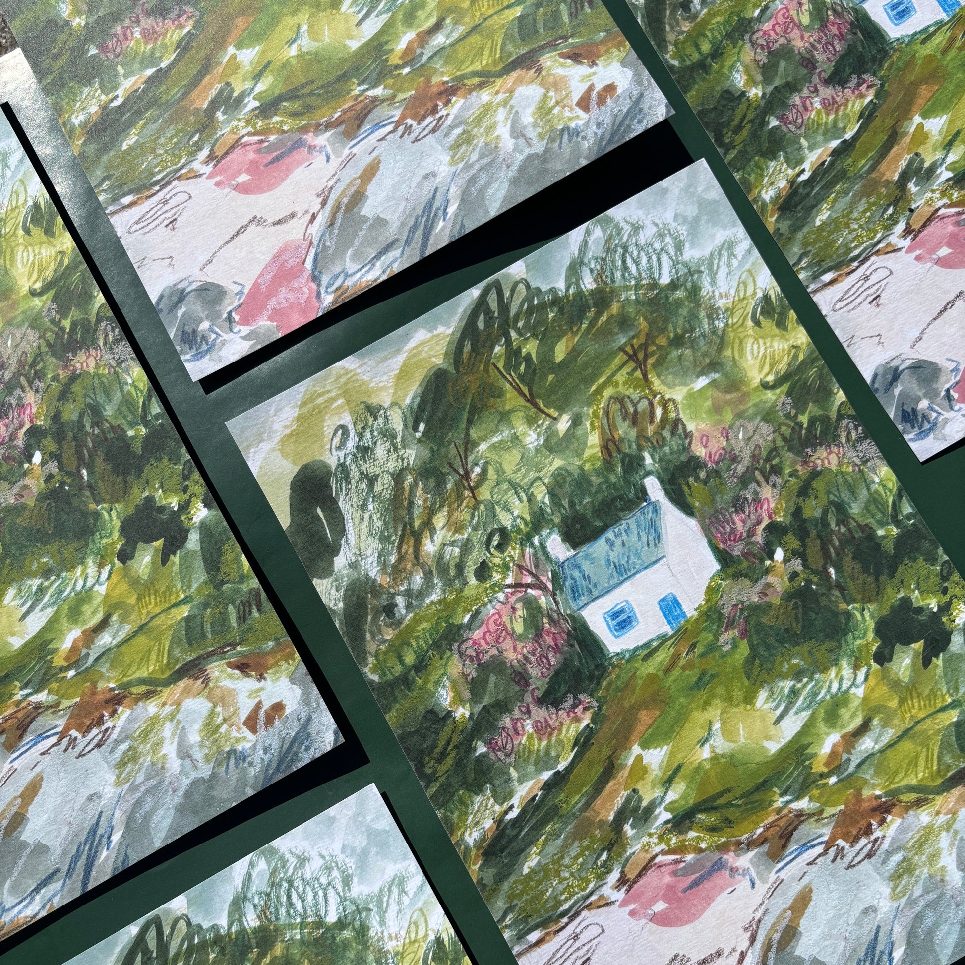 Multiple art prints featuring paintings of a scenic seaside cottage