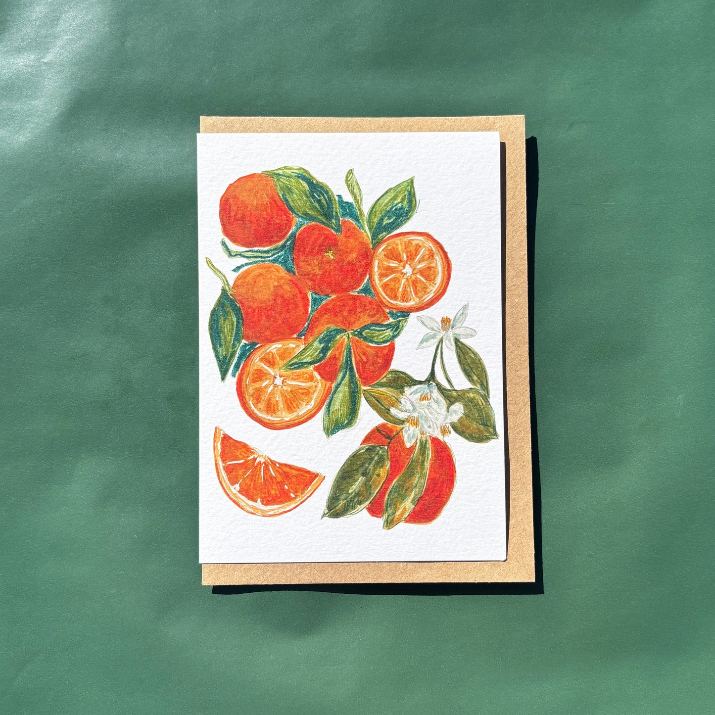 A greeting card featuring a painting of oranges and flowers
